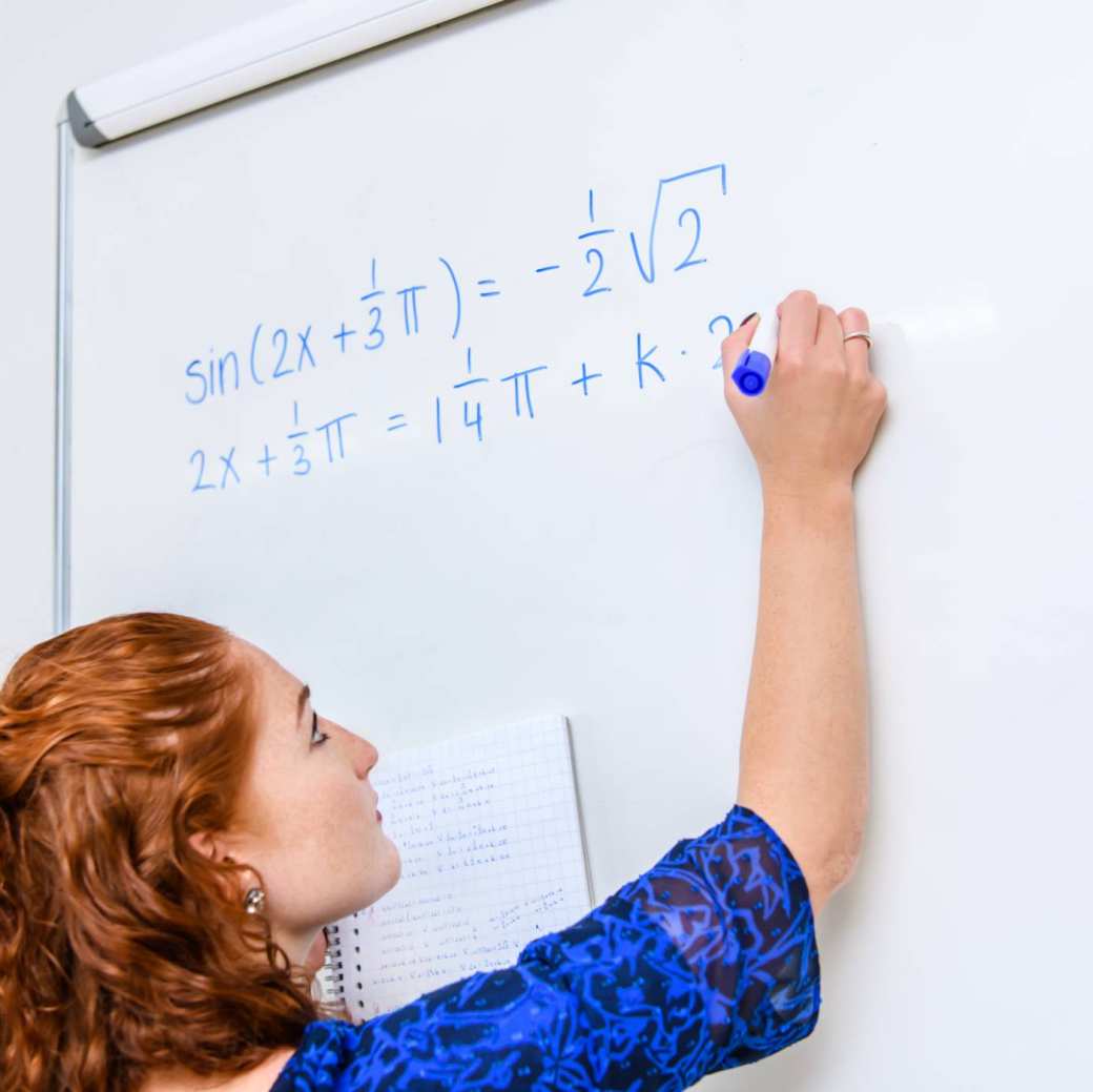 1e9043c6-0ce6-11ee-bc3d-02565807075b Wiskunde studente schrijft een wiskundige formule op het bord met een blauwe stift. 