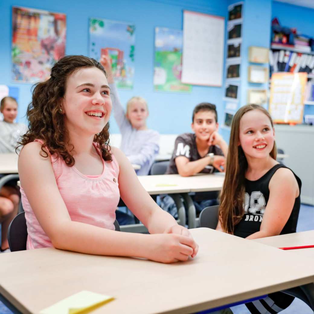 Foto van zijaanzicht van kinderen die lachend in de klas zitten.