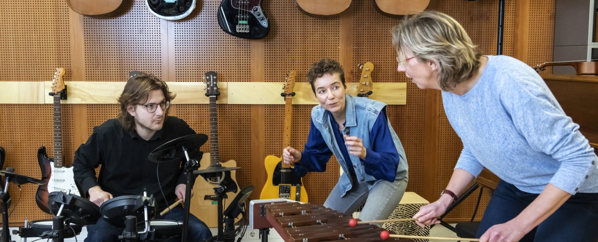 een docent en twee studenten van de han master vaktherapie muziektherapie maken samen muziek op een drumstel en marimba