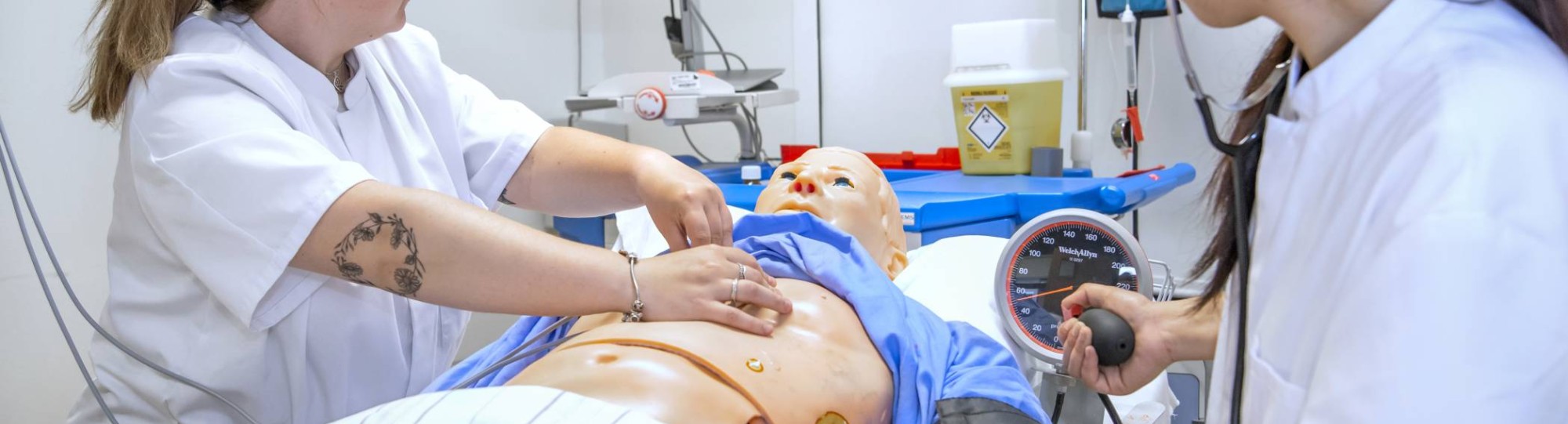 Medische Hulpverlening studentes maken een hartfilmpje van een pop in een praktijklokaal