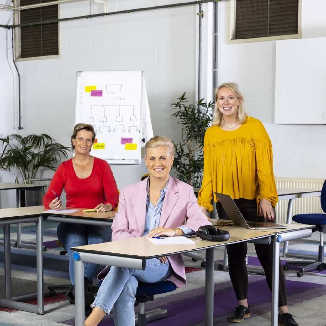 Drie personen achter een tafel in een klaslokaal op de campus op de opleiding learning & development deeltijd