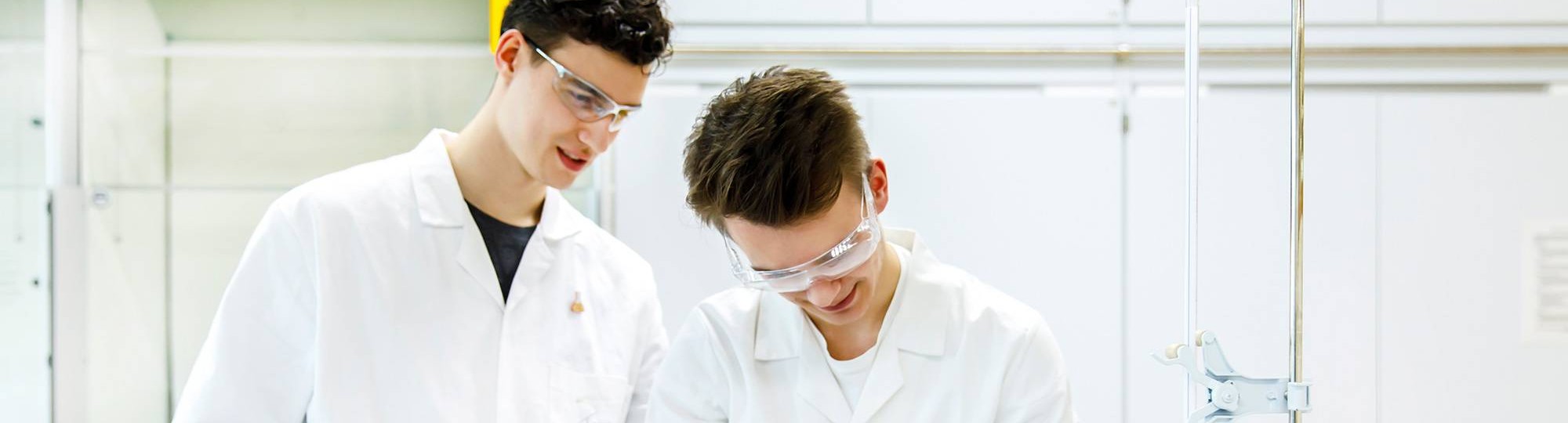 Twee studenten in labjassen controleren de uitkomst van hun experiment.