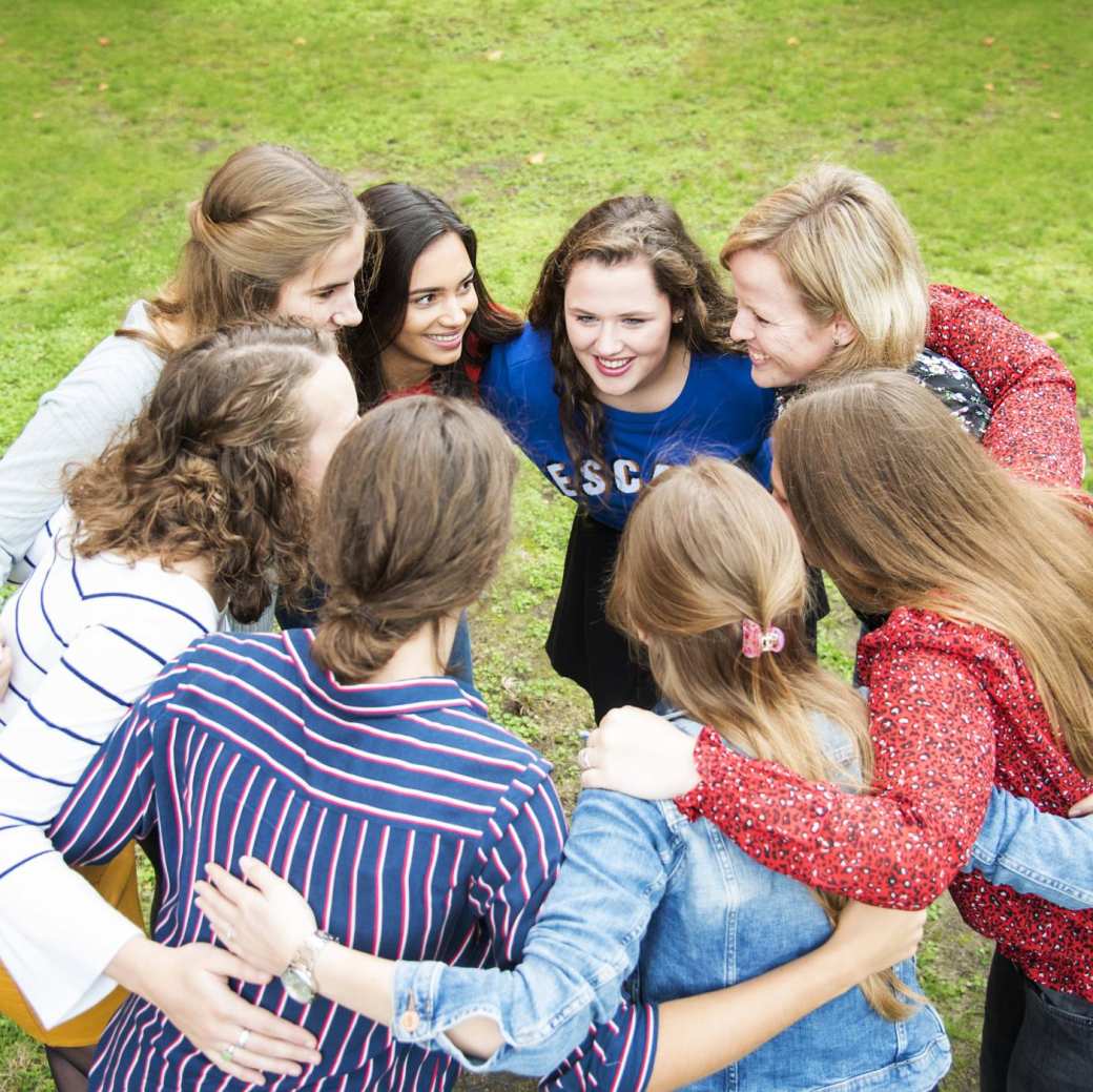 8x gezondheid studenten omarmen elkaar in een kring terwijl ze buiten op het gras staan