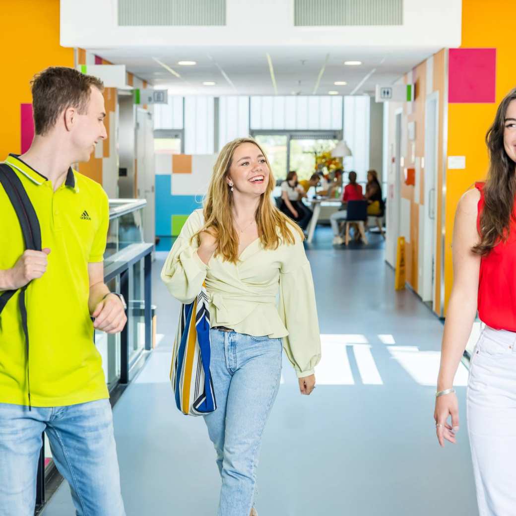 347962 Drie studenten (2 jongen en 2 meiden) wandelend in gang K33. 