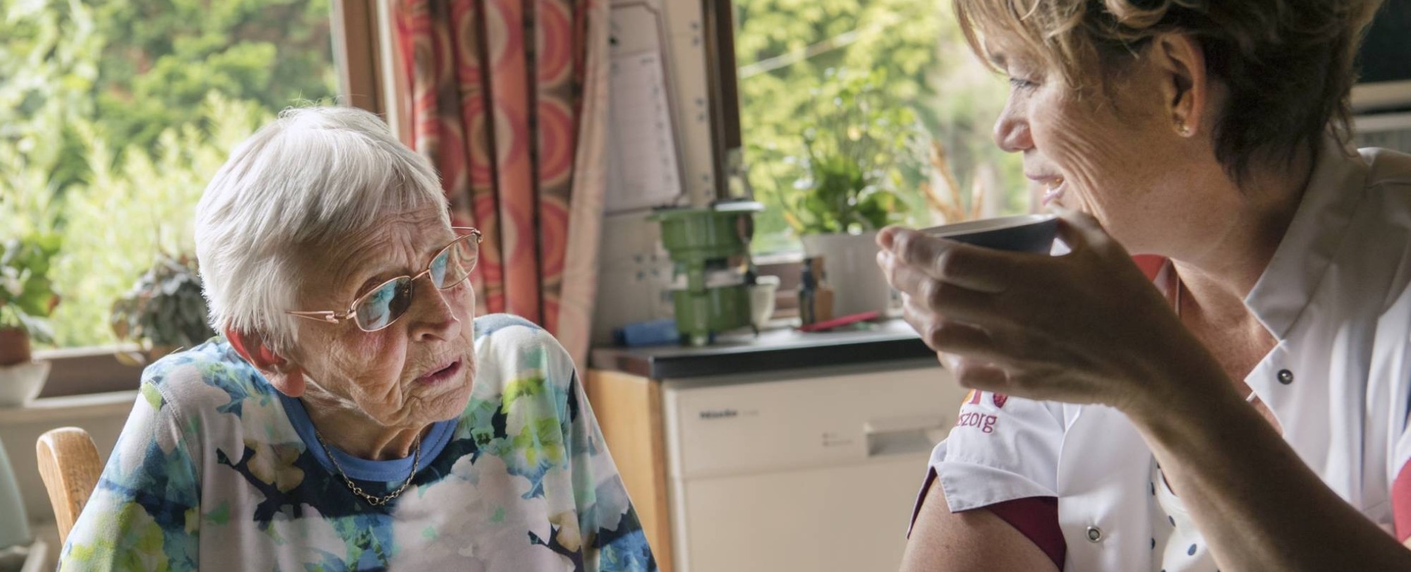102281 een thuiszorgverpleegkundige helpt een nog thuiswonende oudere dame met beginnende dementie bij de dagelijkse zorgtaken