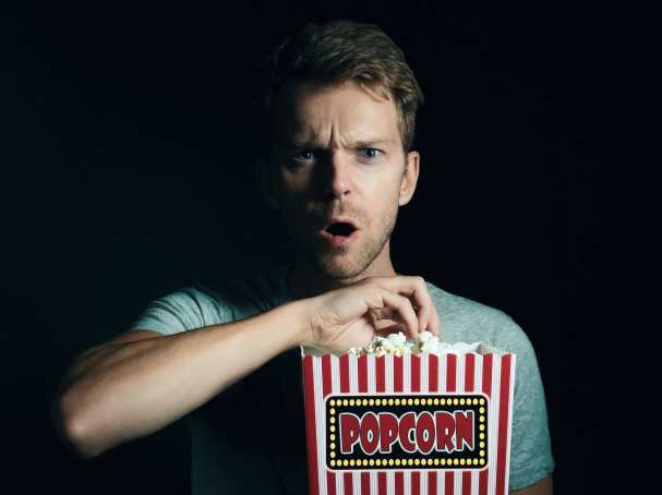 Man eet popcorn terwijl hij film kijkt