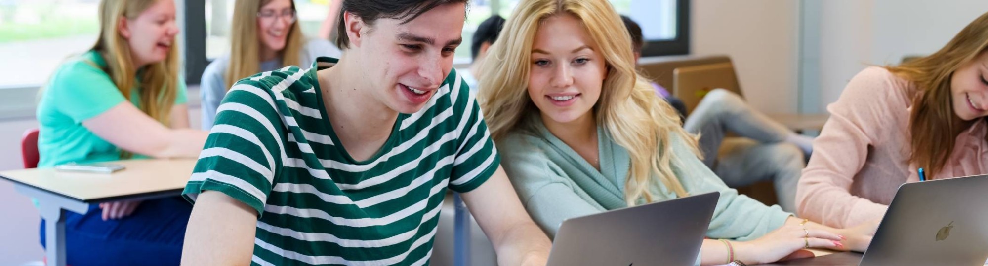 meerdere studenten van bedrijfskunde in een klaslokaal, twee studenten kijken naar een laptop