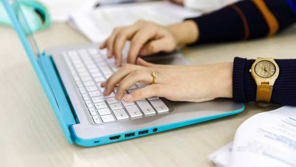 30476 Twee vrouwenhanden typen op het toetsenbord van haar laptop.