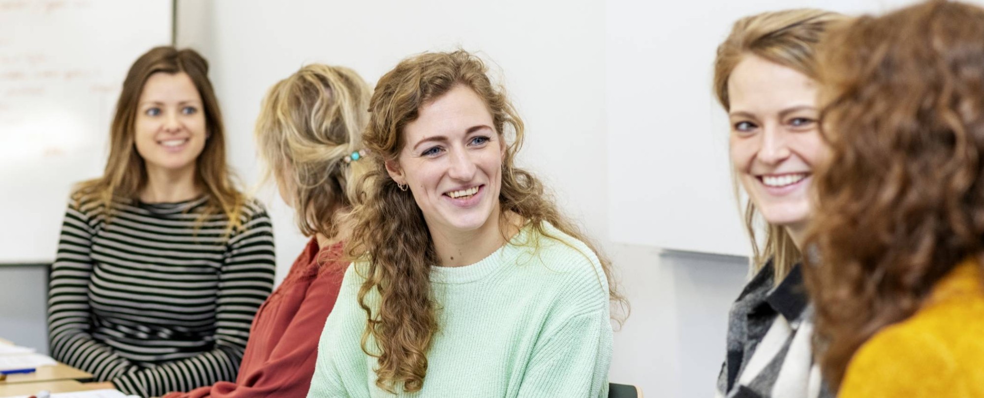 Lachende masterstudenten overleggen samen tijdens een klassikale les onderzoek op de HAN in Nijmegen