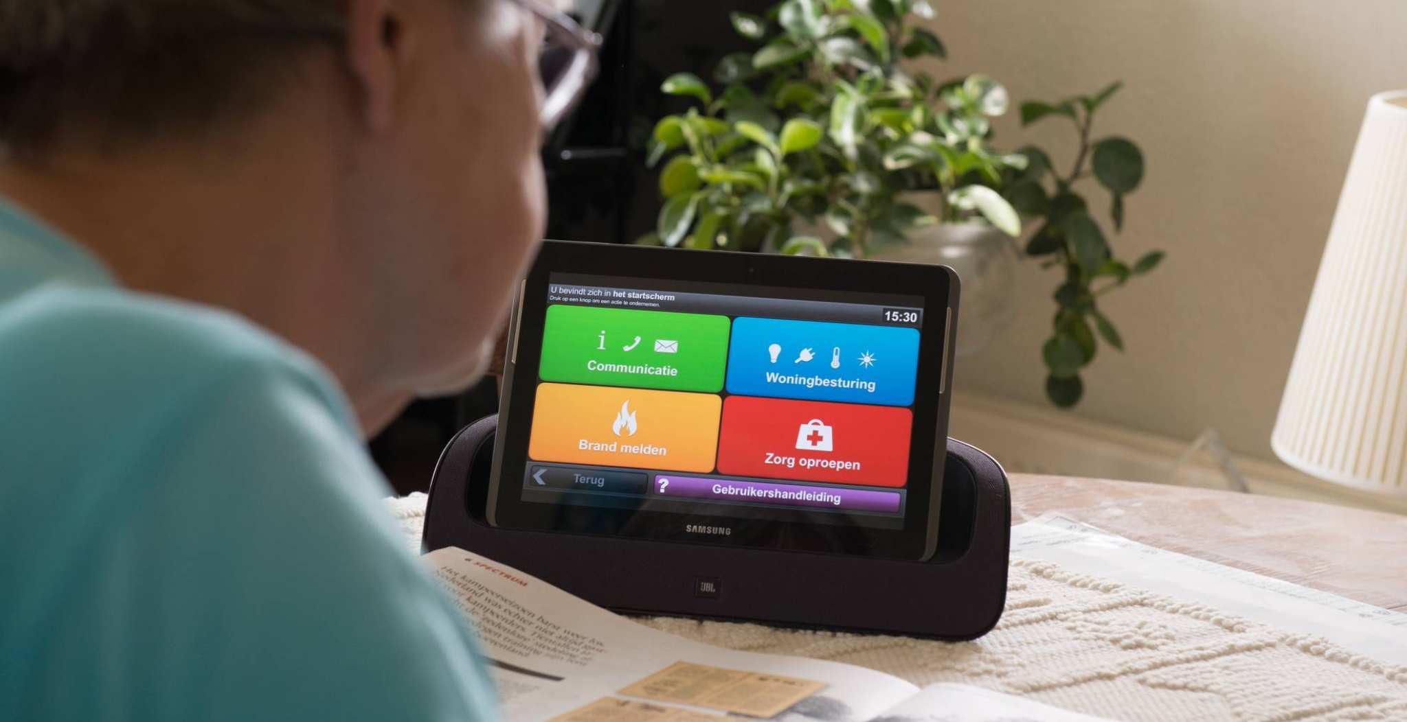 oudere dame gebruikt een tablet met een woningcommunicatiesysteem waardoor ze langer zelfstandig kan blijven wonen
