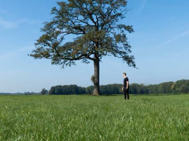 361195 Foto van Finance & Control-student Mylan ter Vrugt in een grasveld voor een boom.