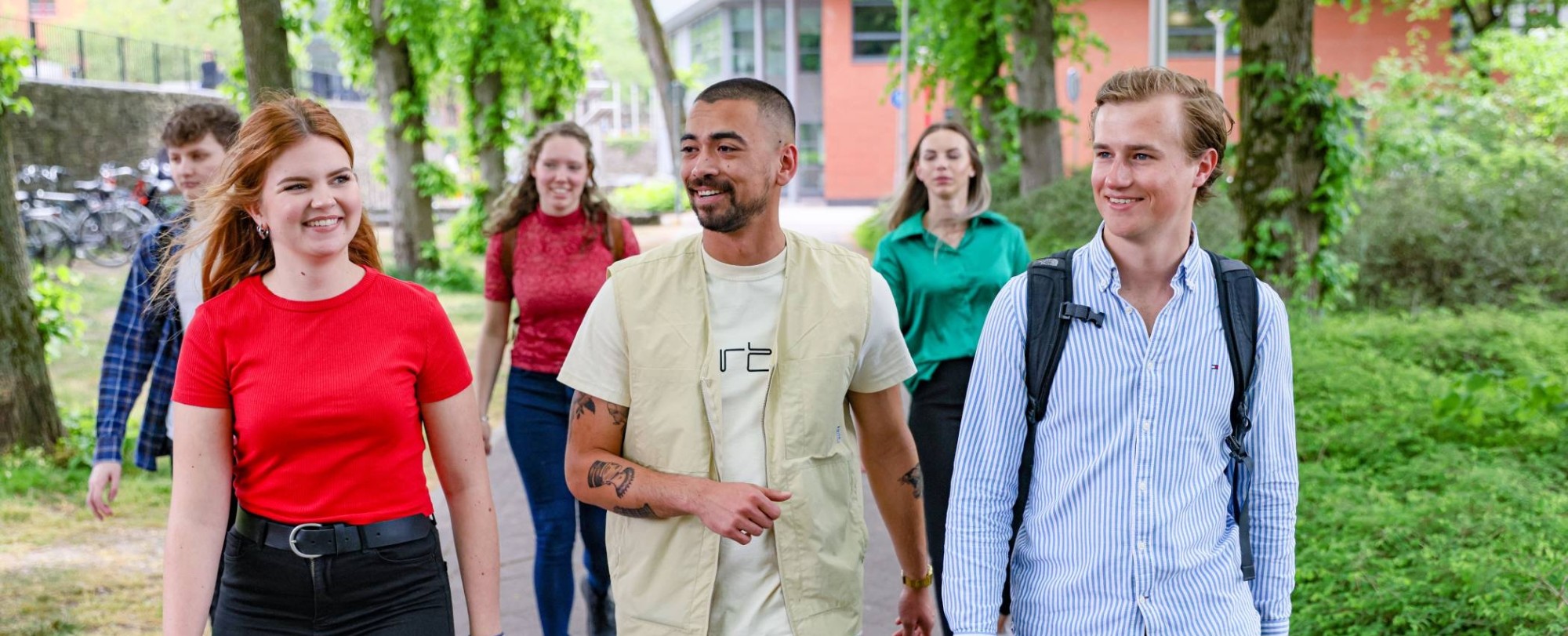 vijf studenten van de opleiding facility management lopen buiten voor het campus gebouw in Nijmegen