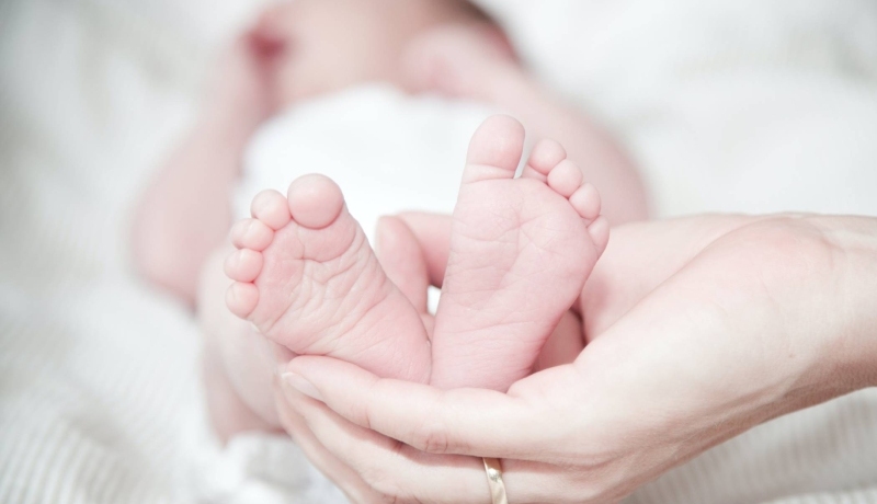 Baby ligt, voeten worden vastgehouden