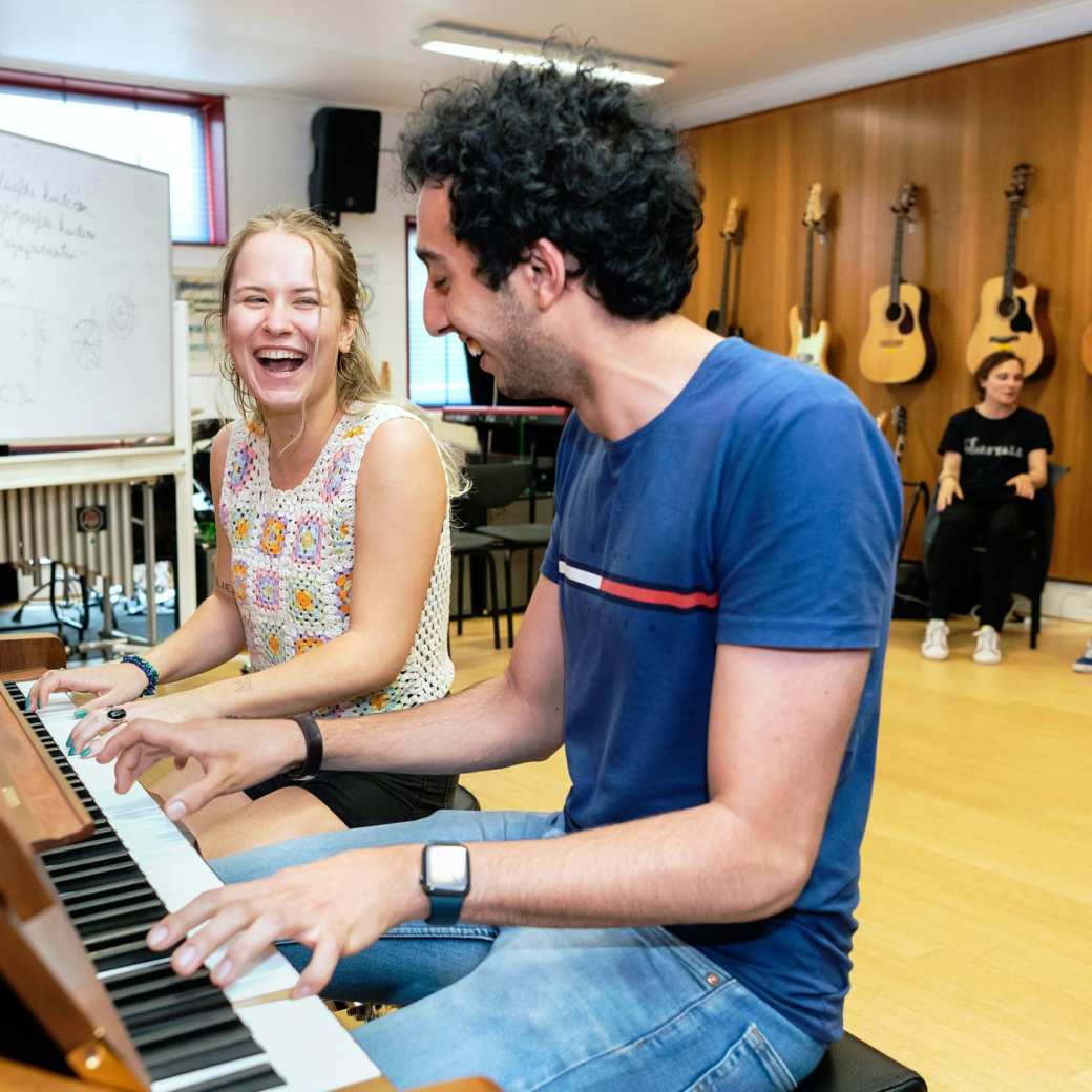 Twee studenten Vaktherapie spelen lachend op de piano