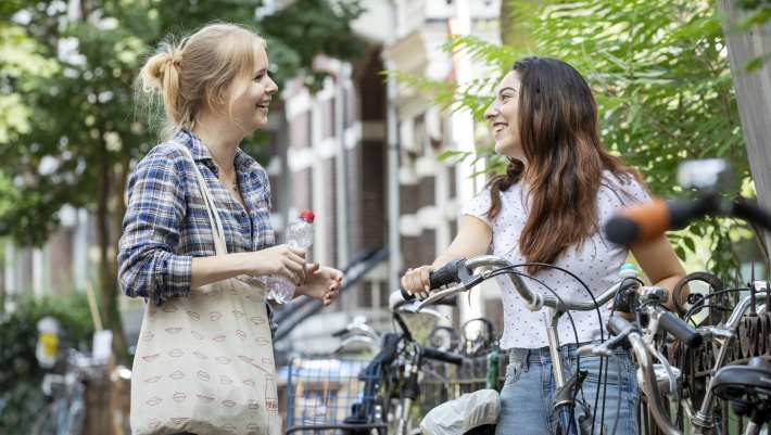 Twee jonge vrouwen praten, een met fiets