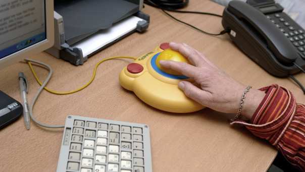 een ernstig spastische patiente werkt achter haar computer met behulp van aangepast toetsenbord en muis