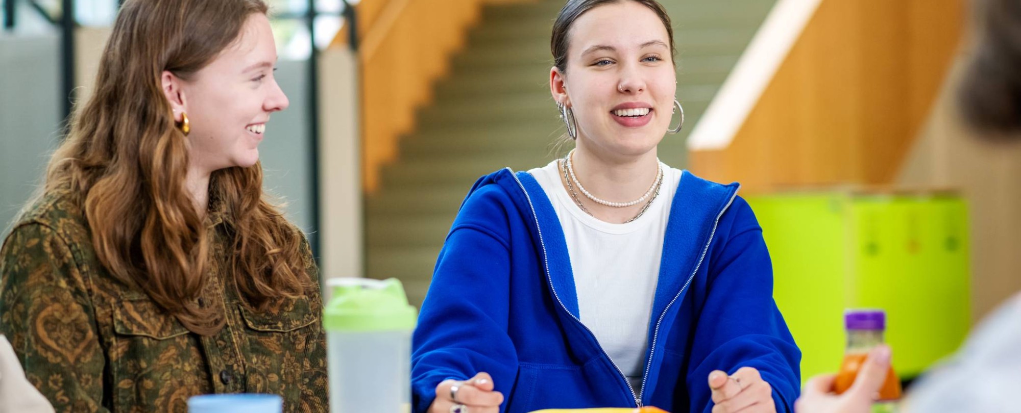 Twee studenten lachen in de pauze.