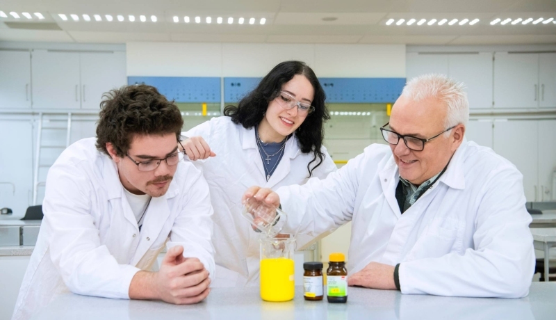 Twee Leraar Scheikunde studenten voeren een proef uit met docent Scheikunde.
