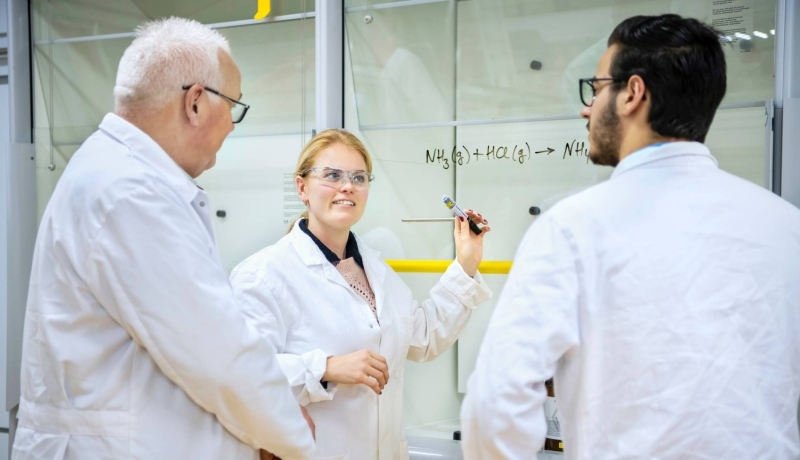 Twee studenten Leraar Scheikunde voeren een experiment uit en hebben een labjas aan en een veiligheidsbril op.