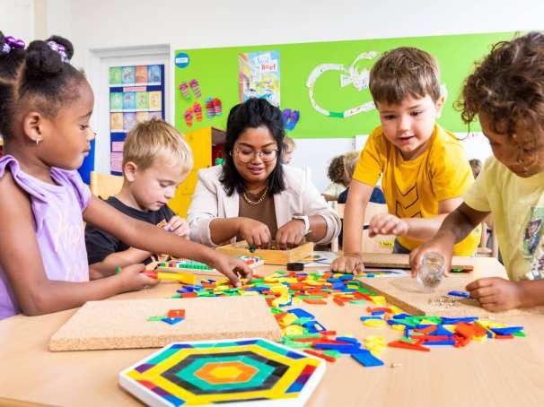 De leerlingen leggen een puzzel en de lerares helpt hen hierbij