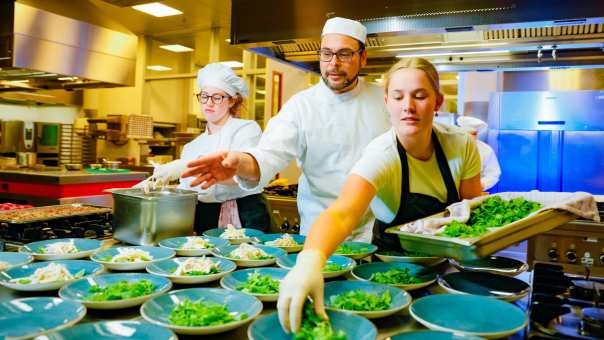 Student legt sla op het bord in de keuken
