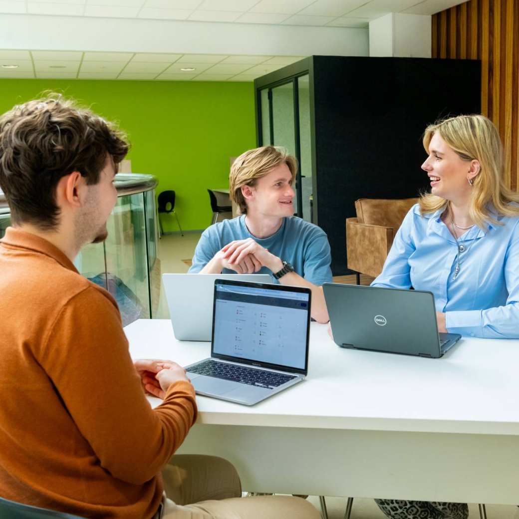 Drie studenten hbo Logistics Management in overleg met laptops erbij
