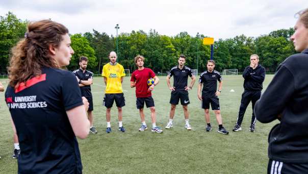 Docent geeft uitleg op het sportveld