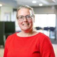 Haren naar achteren vast gestoken, brildragend. Rode trui