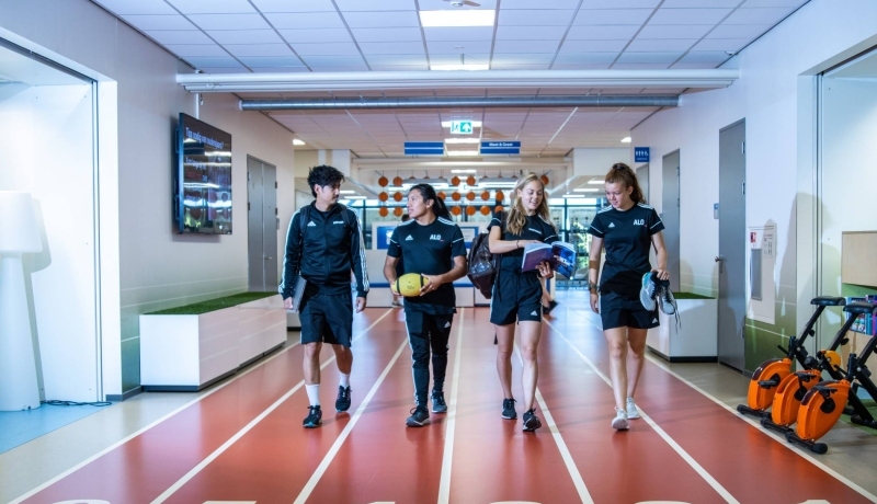 sportkunde en alo samen liggende foto studenten lopen over atletiekbaan binnen bij gymnasion veraf esteban selena carlijn randy 2022
