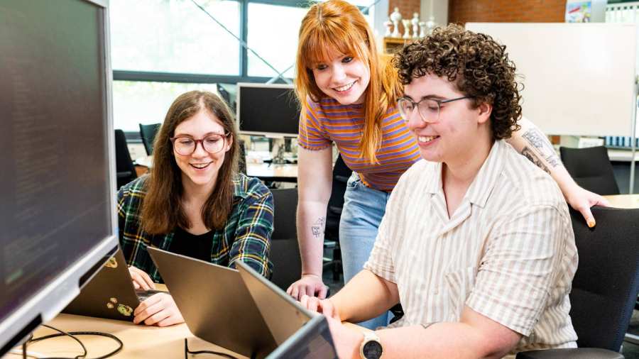 Drie cursisten programmeren in Python achter de laptop