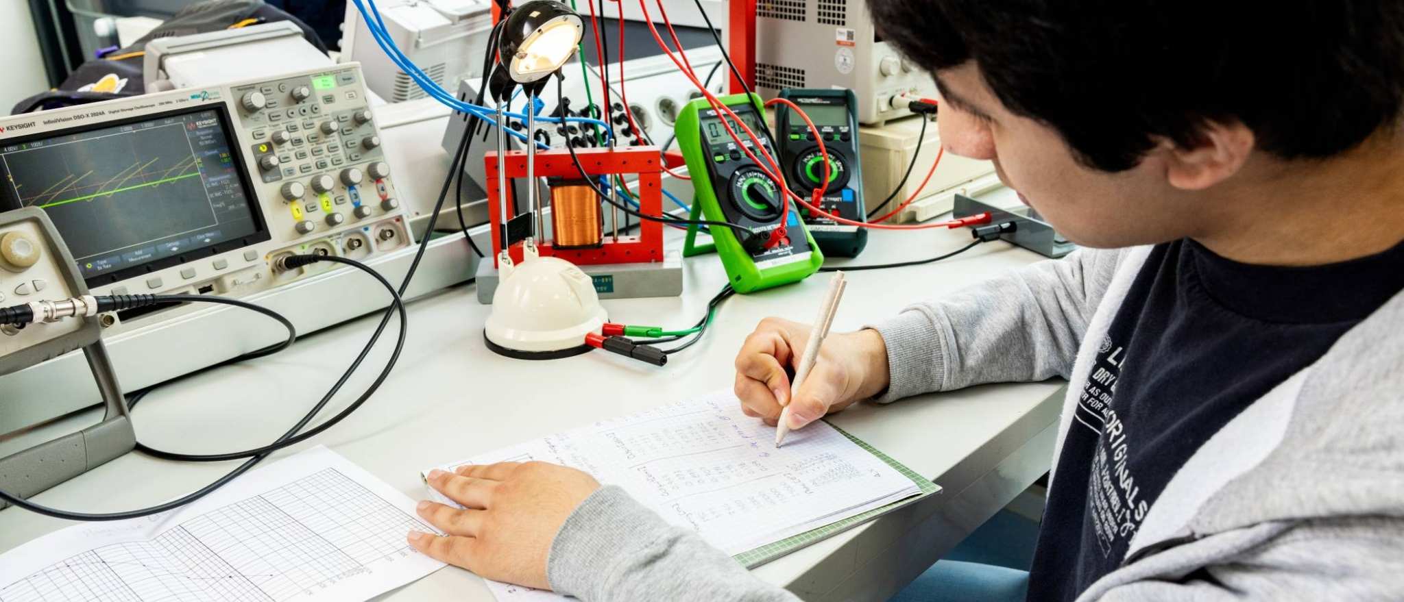 Een student elektrotechniek werkt aan een logboek tijdens het netwerkpracticum.