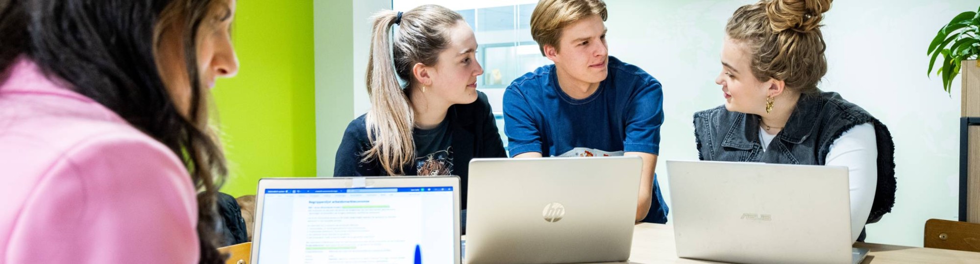 Studenten Human Resource Management (HRM) overleggen in de studio met de laptop erbij