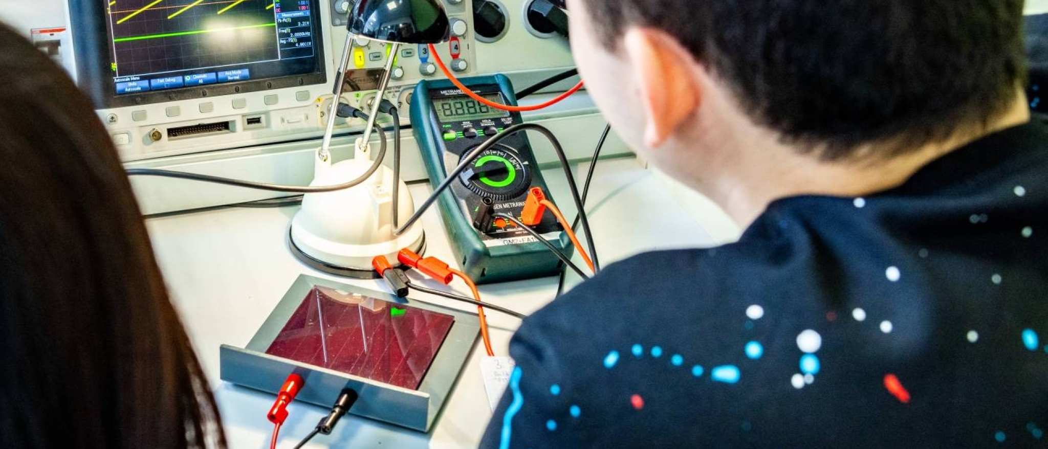 Twee studenten elektrotechniek doen een experiment met een zonnepaneel.