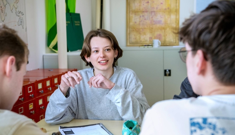 Studente Leraar Aardrijkskunde wijst Zuid-Amerika aan op de wereldkaart die aan de muur hangt.