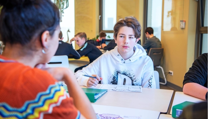 jongen luistert naar docent aan tafel