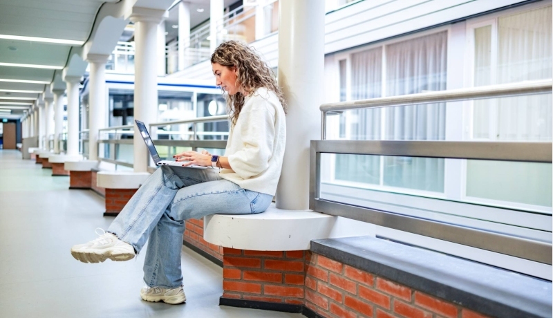 Student van de bachelor Commerciële Economie deeltijd, duaal in gang met laptop.