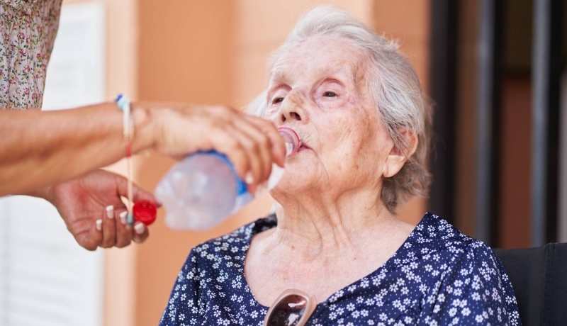 Oudere vrouw krijgt water toegediend