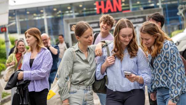 Groep voltijdstudenten kijkt op een telefoon voor Ruitenberglaan 26 in Arnhem.