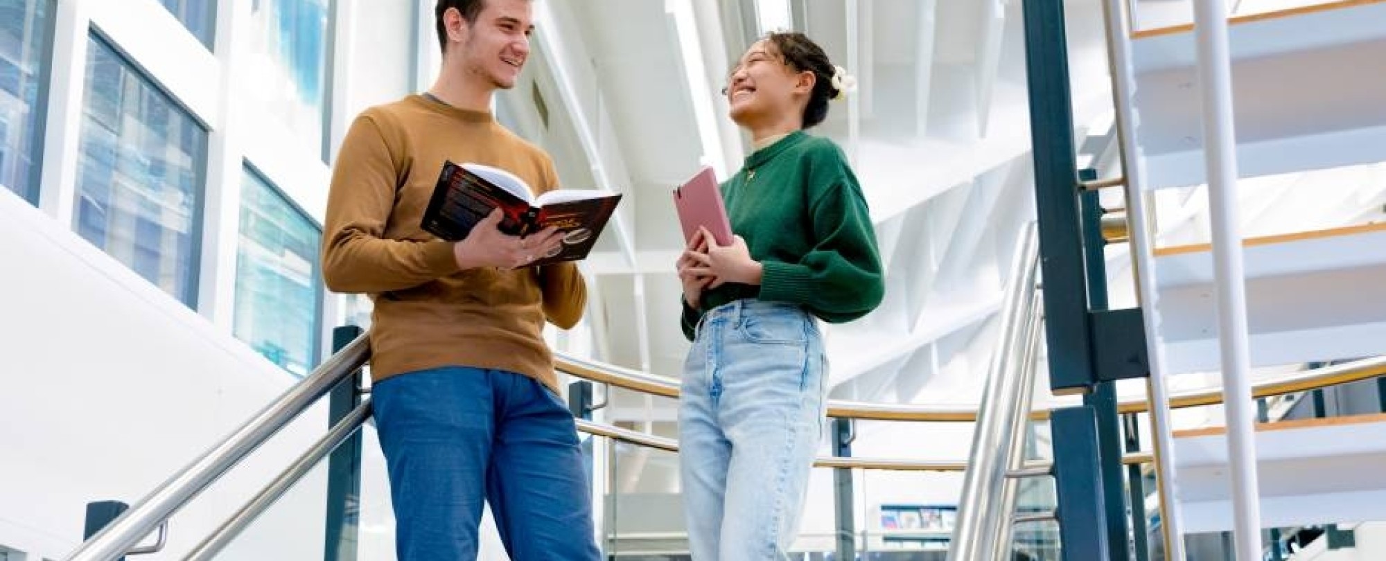 International students Tam and Andrei discussing a book in the library at the Arnhem campus of HAN University of Applied Sciences.