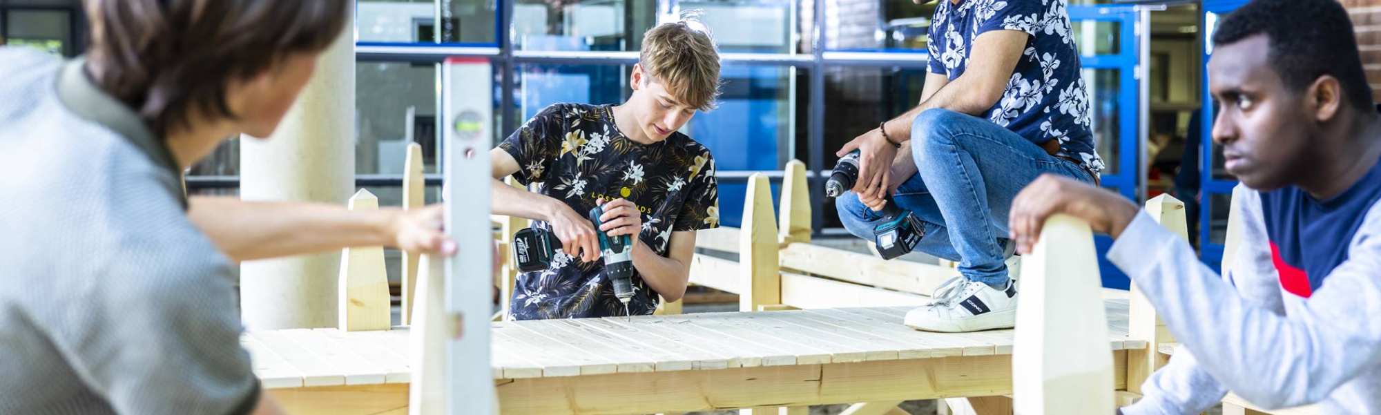 4 studenten civiele werken aan de houten steiger onder het gebouw van de opleiding