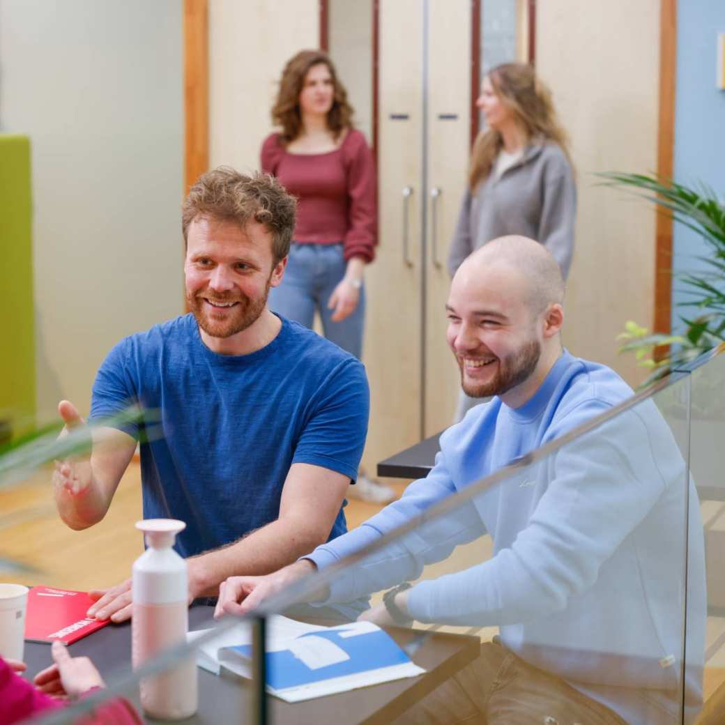 Studenten lachen op de gang aan de tafel