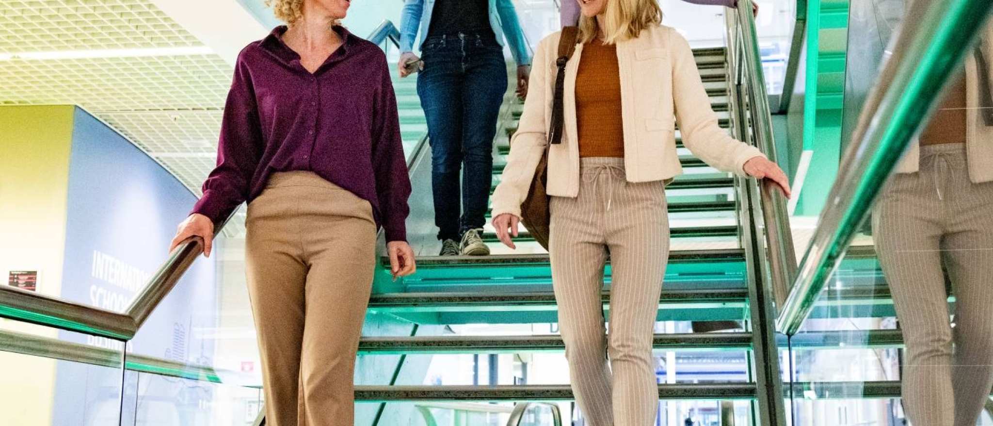 Studenten van Logistiek deeltijd wandelen door de gang en op de trap in hun pauze