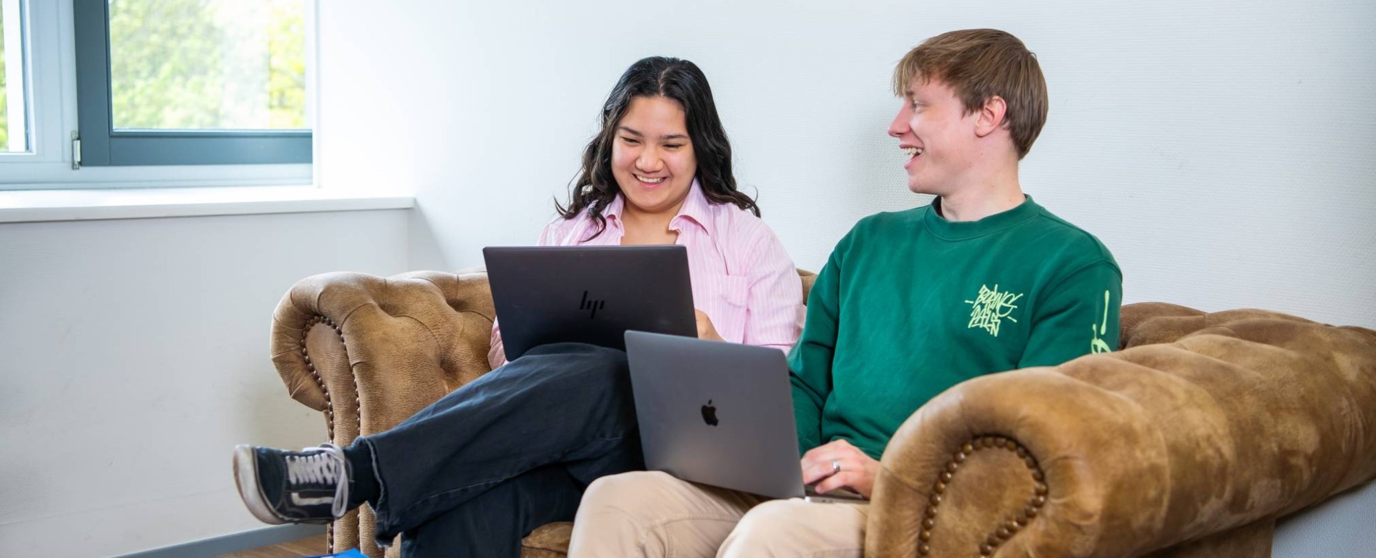 Twee studenten van hbo Toegepaste Psychologie zitten op een bank met de laptop