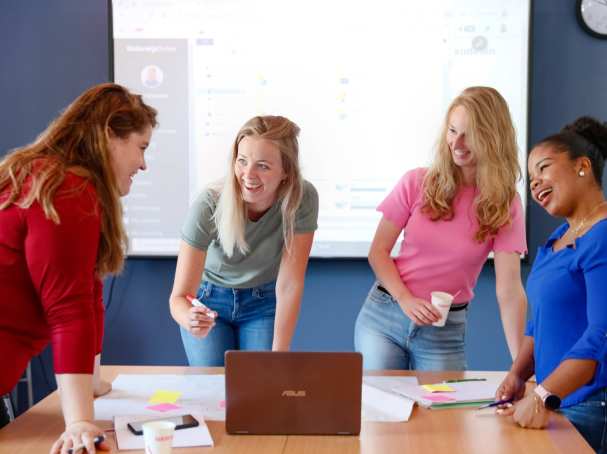 HBO studenten staan om de tafel en voeren projectoverleg met een flipover vel.
