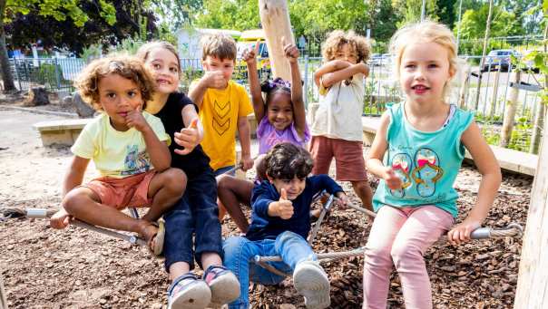 Zeven kinderen poseren buiten op het klimnet. Foto van de opleiding leraar basisonderwijs 