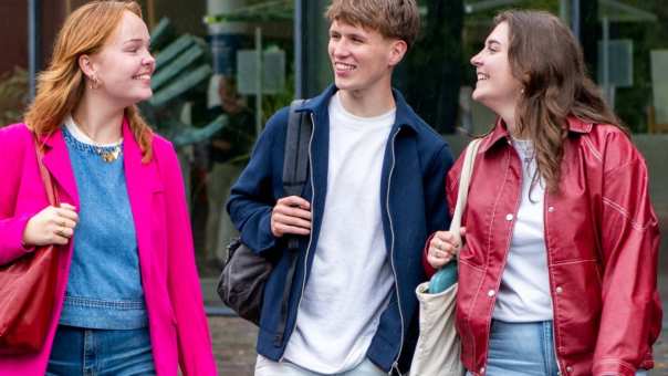 Studenten Ergotherapie lopen bij de hoofdingang van de HAN campus naar buiten en kijken elkaar aan