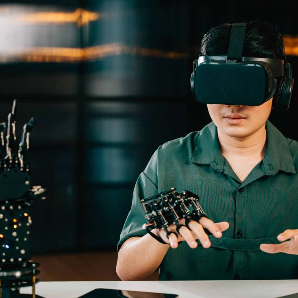 Afbeelding van een jongen met een VR-bril op die een robot hand bestudeert