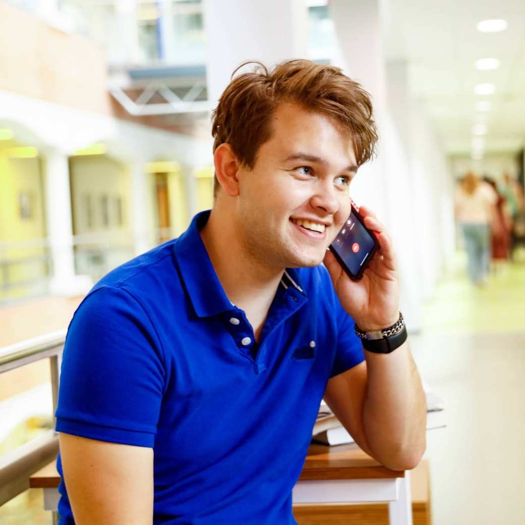 man bellen telefonisch overleg student hal gang