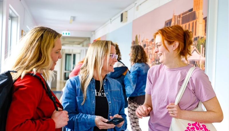 Vrouw laat iets zien op mobiel en de andere moet daarom lachen