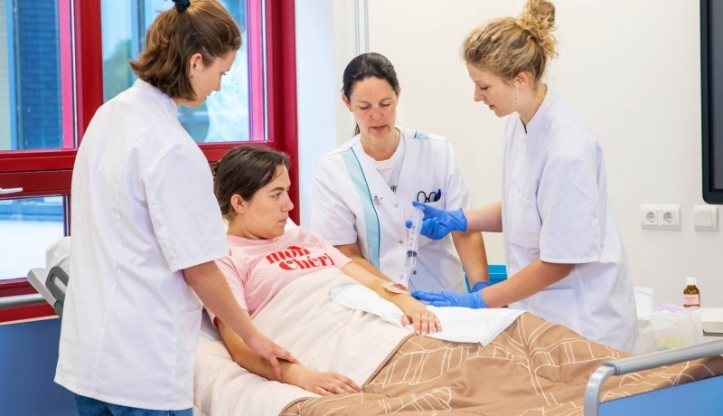 Studenten en docent Verpleegkunde bezig tijdens praktijkles